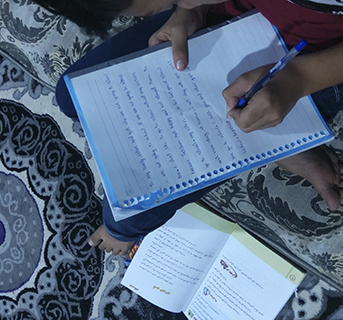 Ein afghanischer Junge schreibt einen solidarischen Brief an seine Schwestern, die nicht mehr zur Schule gehen dürfen. © Save the Children 