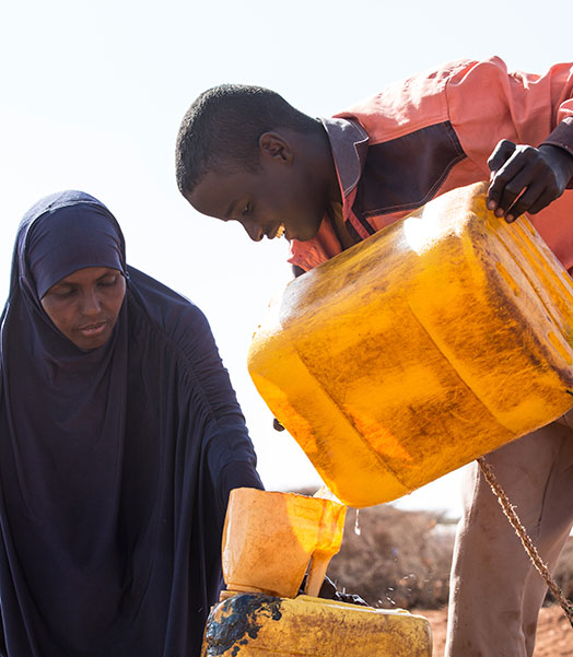 Mutter erhält Wasser aus Kanister von Save the Children Mitarbeiter