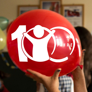 Roter Luftballon mit Logo von 100 Jahre Save the Children 