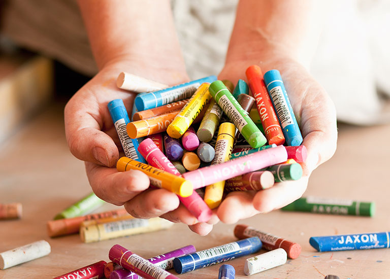Kinderhände mit Wachsmal Stiften in Projekt von Save the Children Deutschland mit geflüchteten Kindern