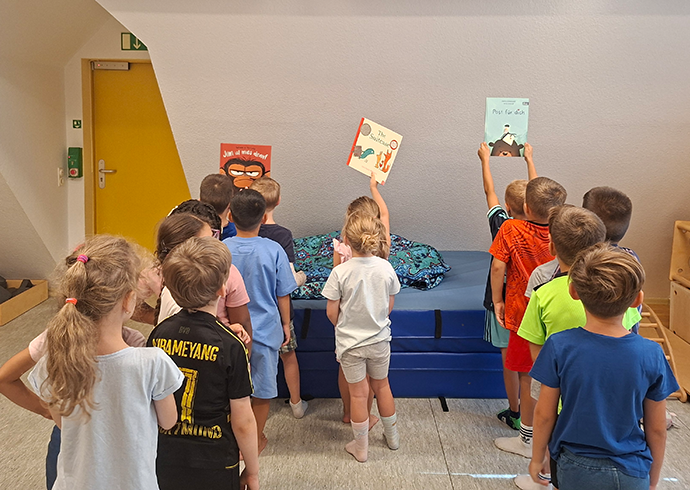 Partizipative Buchauswahl © Save the Children Kinder halten Bücher vor einer Gruppe hoch, um eine Buchauswahl zu treffen.