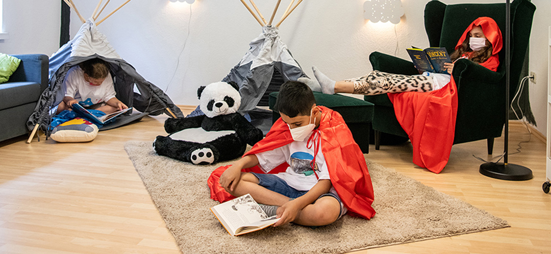 Kinder sitzen in Bücher vertieft in einer gemütlich eingerichteten LeseOase.