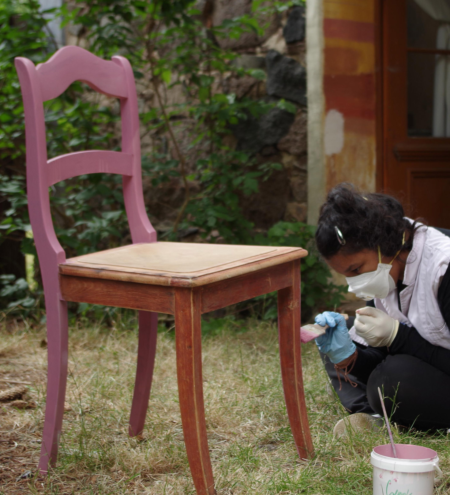 Mädchen streicht einen Stuhl neu an 