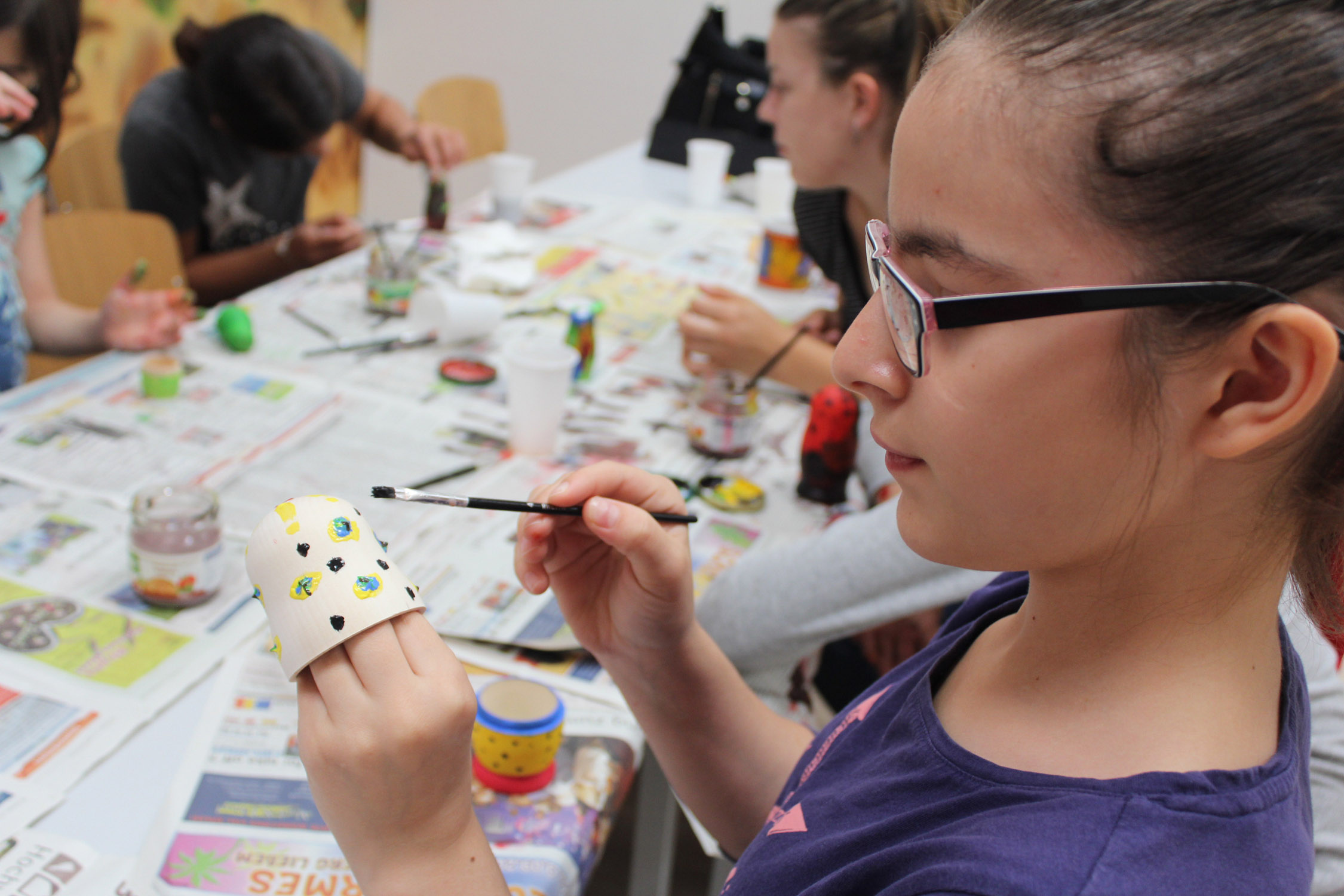 Mädchen malt Becher mit Pinsel und Farbe an 