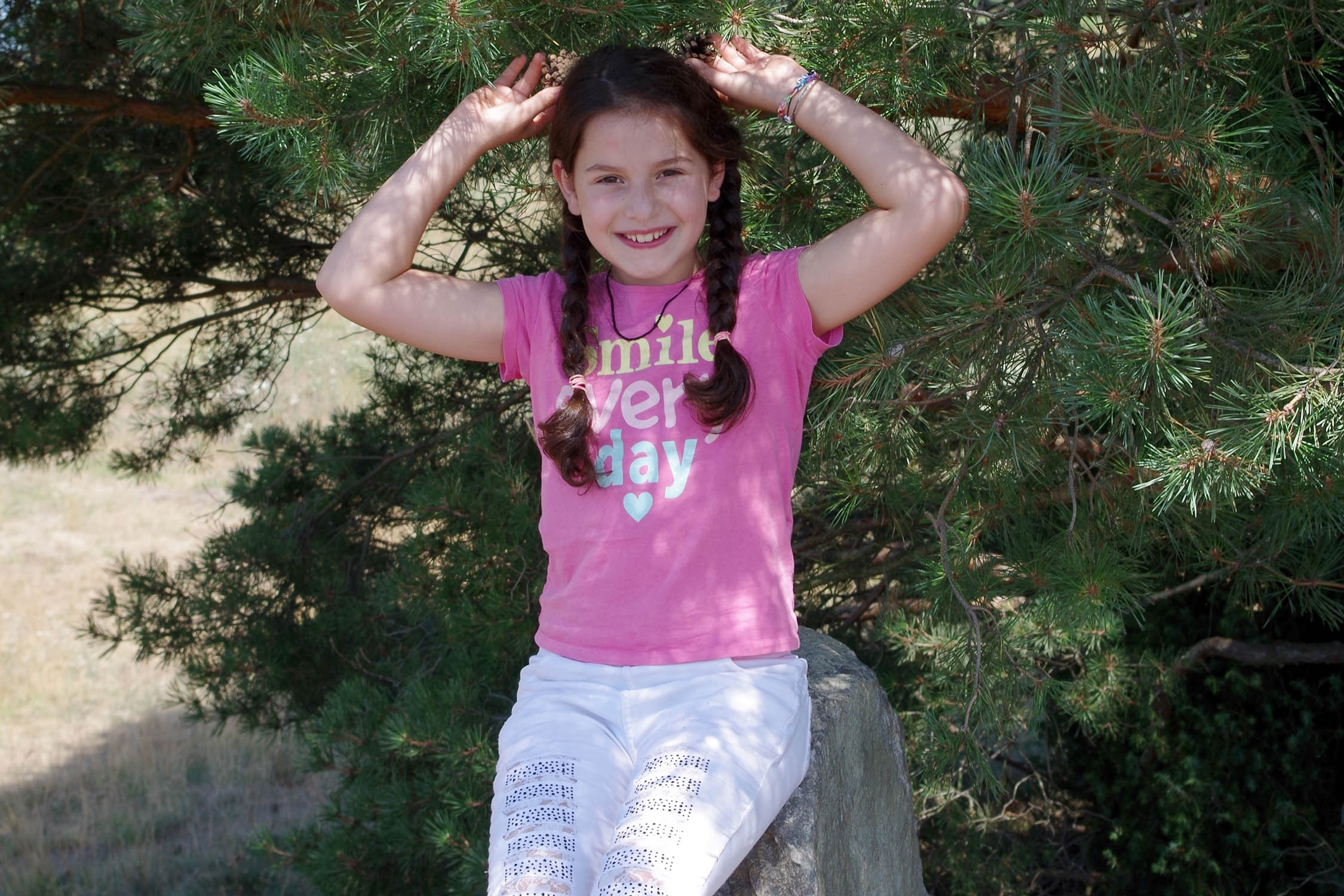 Mädchen posiert vor einem Nadelbaum