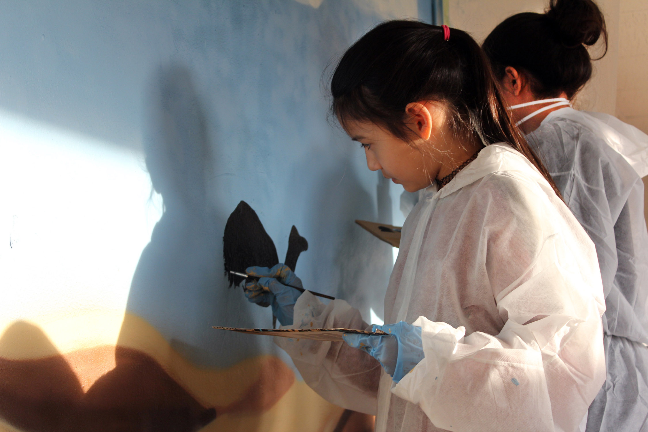 Mädchen bemalen Wand im Projekt Mädchen.Machen.Mut von Save the Children