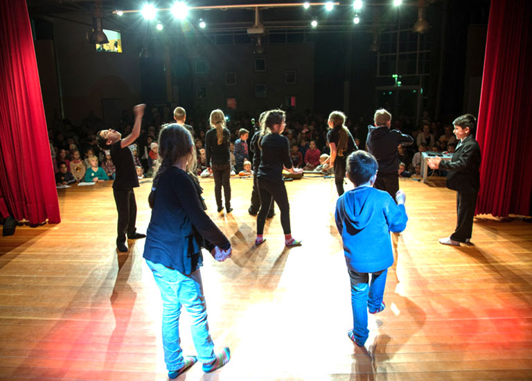 Kinder performen auf einer Bühne vor Publikum