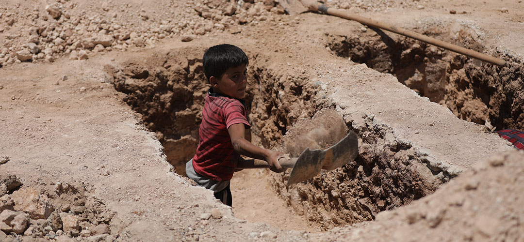 Ein acht Jahre alter Junge in Syrien schaufelt ein Grab auf einem Friedhof aus. 