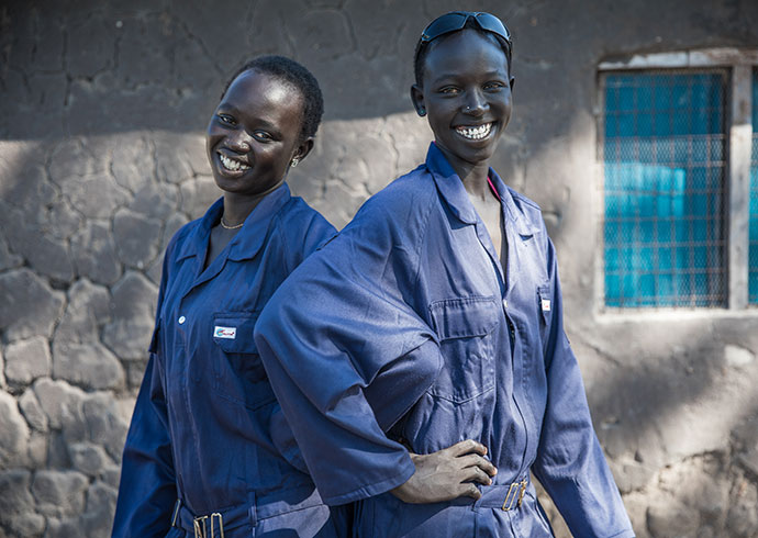 Zwei Mädchen aus dem Südsudan in Arbeitskluft. Sie arbeiten als Schweißerinnen. 