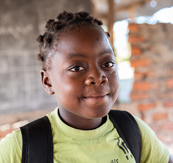 Ein Mädchen aus Mosambik steht vor ihrer Schule, die vom Zyklon zerstört wurde. 