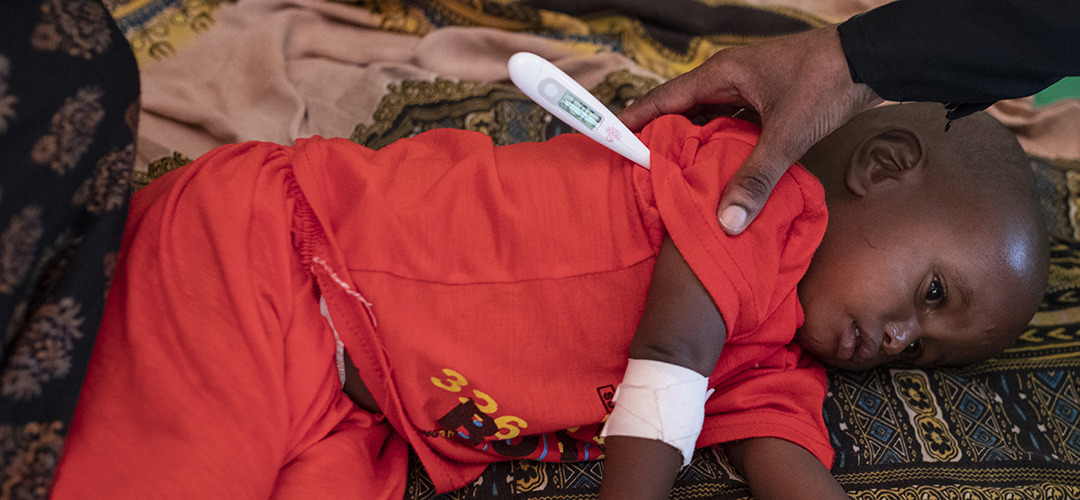 Eine Krankenschwester misst bei einem mangelernährten Kind aus Ostafrika Fieber.