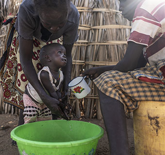 Eine kenianische Mutter wäscht ihrem kleinen Kind die Hände. © Fredrik Lerneryd / Save the Children