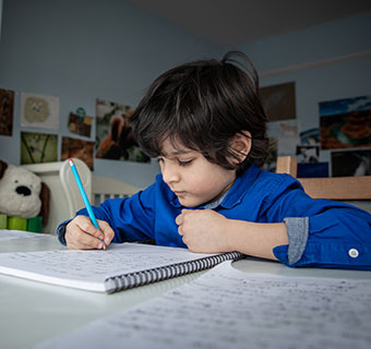 Ein Junge arbeitet zu Hause am Schreibtisch. © Jonathan Hyams / Save the Children