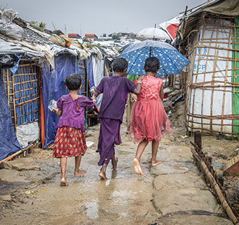 Kinder im Monsun-Regen im größten Flüchtlingscamp der Welt in Cox's Bazar. Auch hier droht der Zyklon Amphan große Schäden anzurichten. Vor den Naturgewalten können sich die Menschen kaum schützen. Ihre Hütten stehen oft an steilen Hängen, sind kaum befestigt und drohen bei aufgeweichtem Boden abzurutschen. © Jonathan Hyams / Save the Children