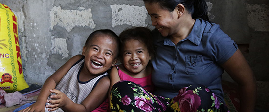 Zwei lachende Kinder mit ihrer Mutter © Lei Tapang / Save the Children
