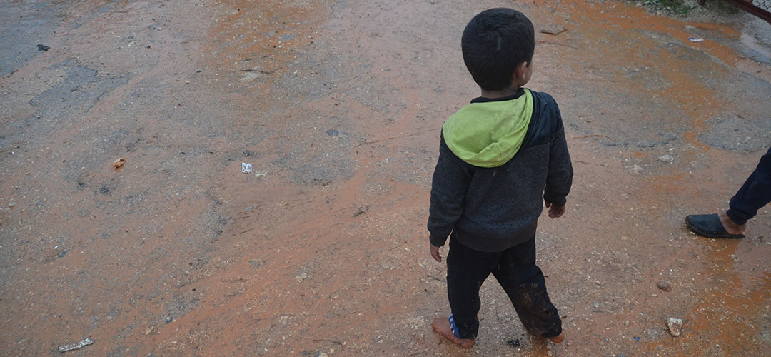  Ein Kind läuft barfuss durch ein Flüchtlings-Camp in Idlib, Syrien.