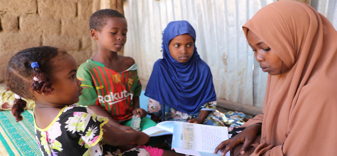 Mahadiya liest ihren Geschwistern aus einem Buch vor, das ihr die mobile Kamelbibliothek gebracht hat. © Save the Children / Seifu Asseged