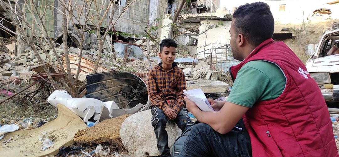 Der Save the Children-Mitarbeiter Mubarak* (rechts) sitzt mit Bara'a*, 11 Jahre alt, im vom Krieg zerstörten Taiz im Jemen.