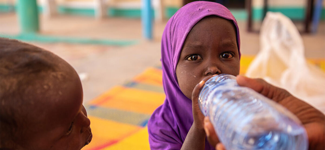 Die Zwillinge Sayid und Salma trinken Wasser in einer Save the Children-Klinik in Somalia, wo sie wegen Unterernährung behandelt werden.