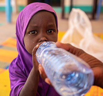 Die zweijährige Salma trinkt Wasser in einer Save the Children-Klinik in Somalia, wo sie wegen Unterernährung behandelt wird.