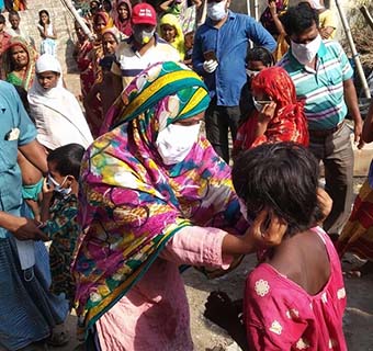 Eine freiwillige Helferin in Indien zeigt anderen in ihrer Gemeinde, wie sie sich mit einer Maske vor Covid-19 schützen können.