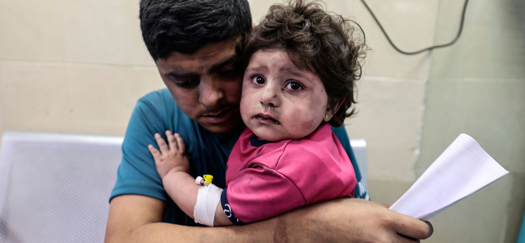Ein Palästinensischer Mann hält ein bei einem Luftangriff verletztes Mädchen im Arm, das im Krankenhaus auf Behandlung wartet. © MAHMUD HAMS/AFP via Getty Images