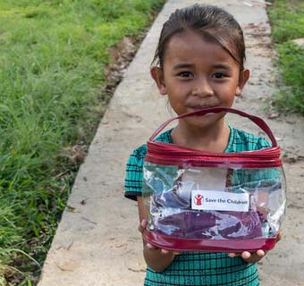 Kemala* aus Indonesien zeigt ihr Hygiene-Kit, das sie von Save the Children erhalten hat.