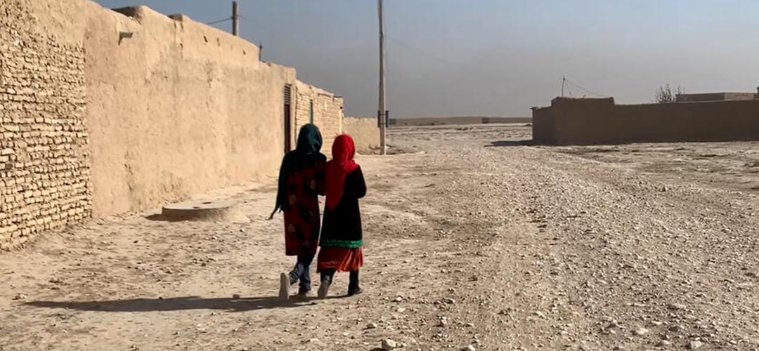 Zwei afghanische Mädchen laufen Seite an Seite entlang einer Mauer. Eine verheerende Dürre trug in Afghanistan zur erneuten Verschärfung der Hungerkrise bei.