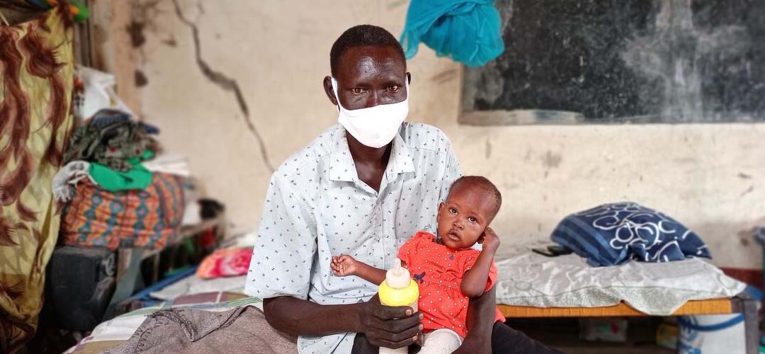 Ein Vater hält seine kleine Tochter in den Armen, die von Save the Children gegen Mangelernährung behandelt wurde.