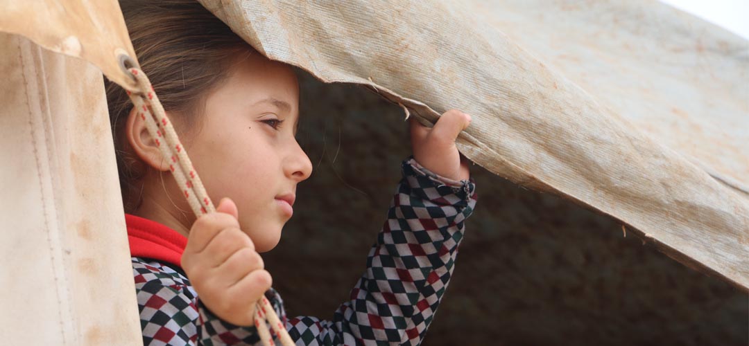 Die siebenjährige Lara* aus Syrien blickt aus ihrem Zelt über das Camp, das nur ein Zuhause auf Zeit sein sollte.