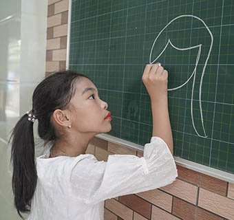 Die achtjährige Mi* malt an eine Tafel, sie und ihre Familie werden während der Pandemie von Save the Children beim Lernen von zuhause unterstützt.