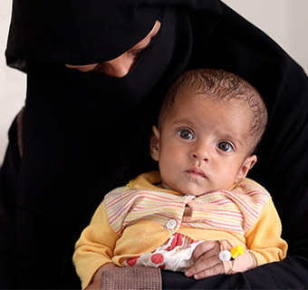 Samah* hält ihre Tochter in den Armen, die aufgrund ihrer Unterernährung in einem Gesundheitszentrum von Save the Children behandelt wird.