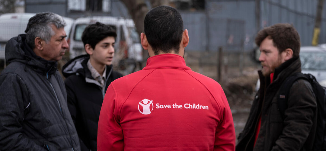 Samad* und sein Vater Mohammad* im Gespräch mit Save the Children-Mitarbeitern in der Nähe des rumänischen Aufnahmezentrums. © Pedro Armestre / Save the Children 