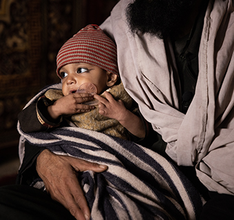 Mohammad* aus dem Norden Afghanistans hält seinen einjährigen Sohn Ninangyali* im Arm, der schwer mangelernährt ist. © Jim Huylebroek / Save The Children 
