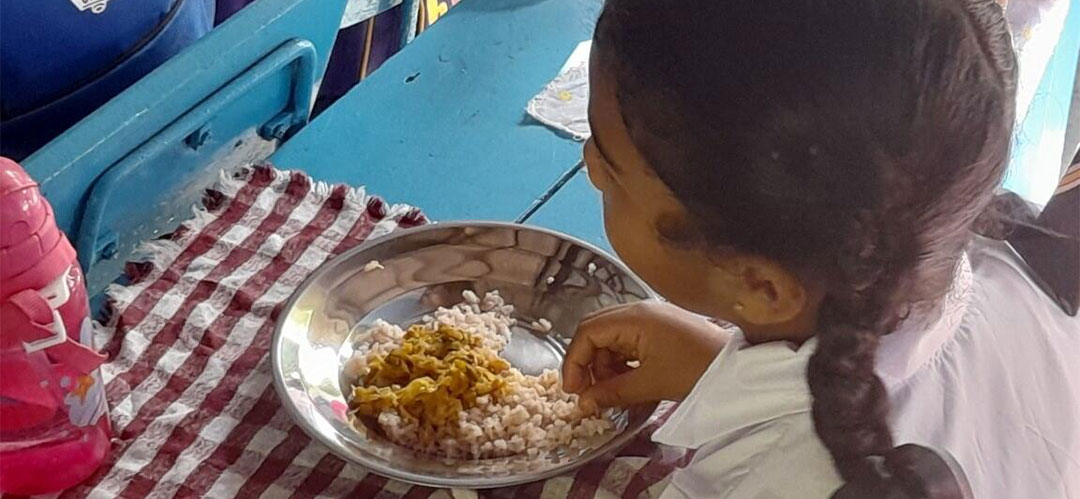 Ein Mädchen isst ihre Schulmahlzeit. Save the Children unterstützt die Verteilung von Mahlzeiten in der Schule und versorgt bedürftige Gemeinden in acht Distrikten Sri Lankas mit Nahrungsmitteln.