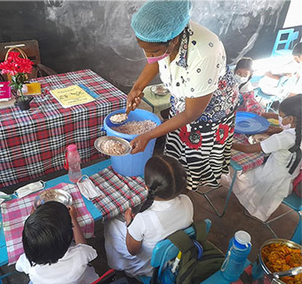 Schüler*innen in Sri Lanka warten auf ihre Schulmahlzeit, die für viele Kinder das einzige warme Essen am Tag darstellt. Nun drohen die Schulspeisungen wegen der Wirtschaftskrise im Land wegzufallen.