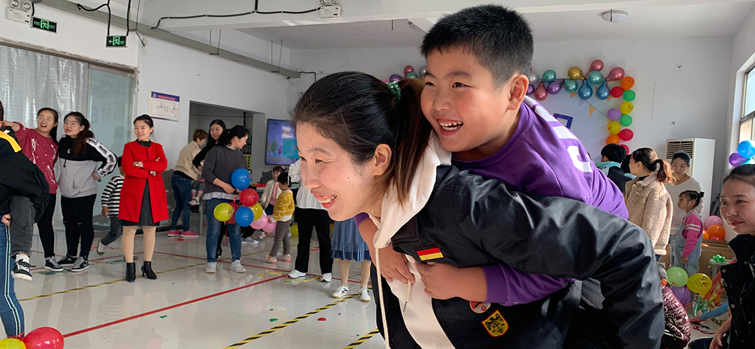 Ein Kind mit seiner Mutter, die Arbeitnehmerin in einer Fabrik in China ist, in der zum Eltern-Kind-Tag vertrauensbildende Aktivitäten durchgeführt wurden.