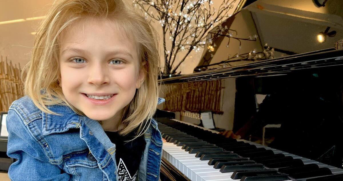 Kind sitzt an einem Klavier und lächelt in die Kamera. © Tea Cheney