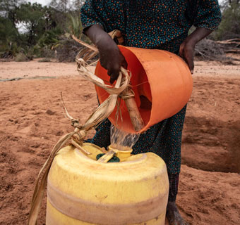 Mahad* füllt Wasser an einem temporären Brunnen in Kenia auf