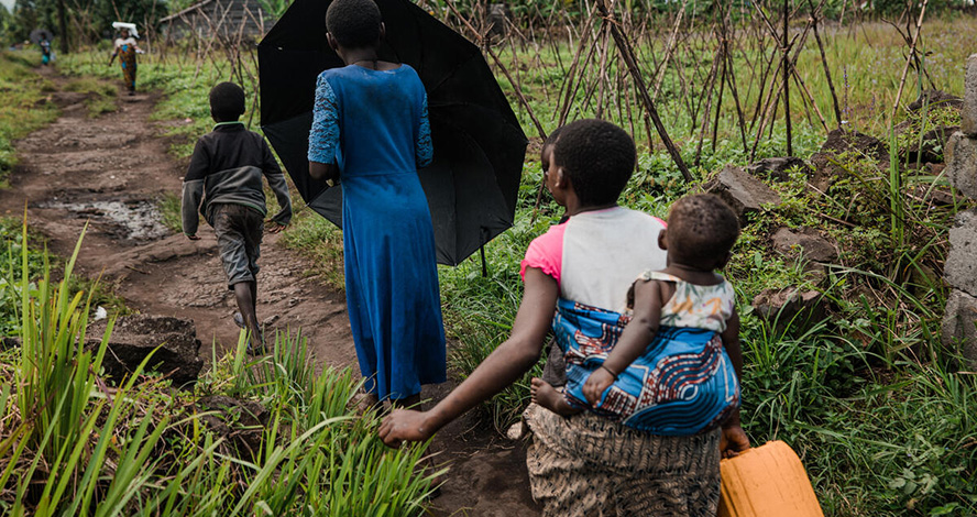 Vier Kinder in der Demokratischen Republik Kongo laufen hintereinander, um Wasser zu holen.