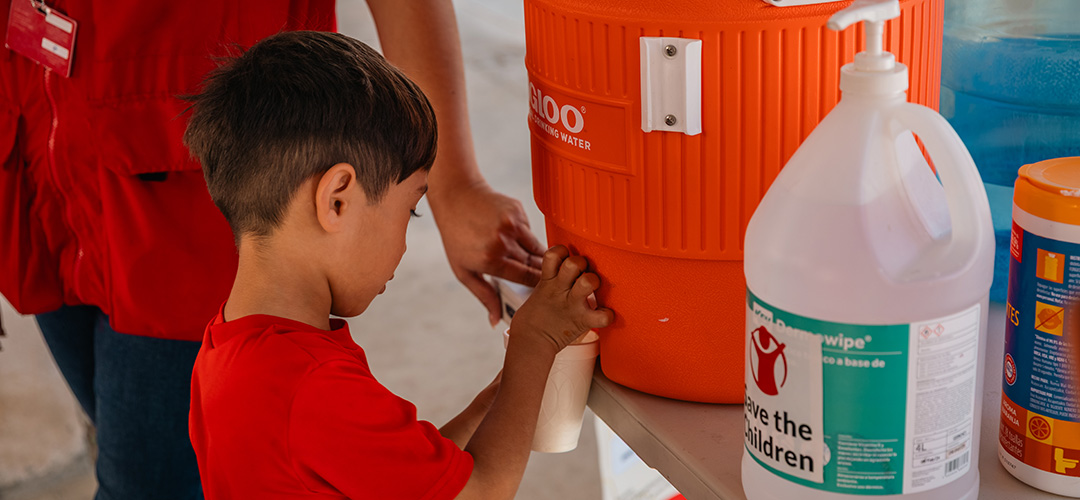 Ein Kind holt sich Wasser von einem Wasserspender von Save the Children. © Miguel Vera / Save the Children Mexiko Ein Kind bedient sich an einem Wasserspender