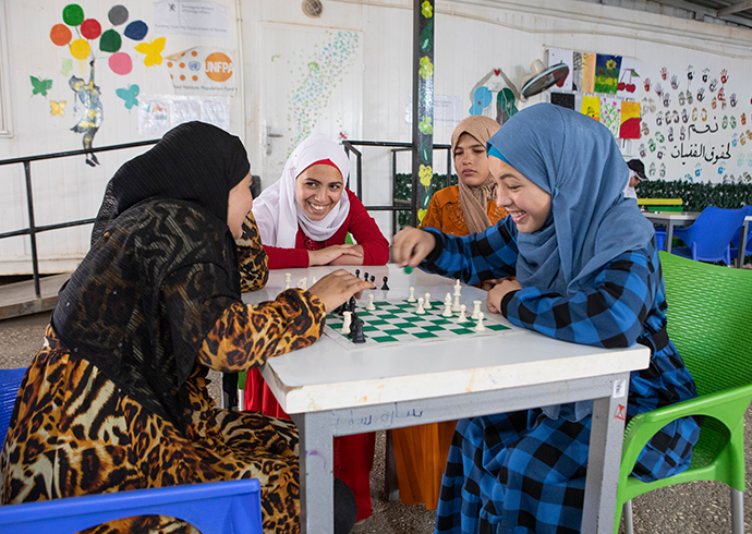 Mehrere Mädchen sitzen gemeinsam an einem Tisch, zwei spielen miteinander Schach.