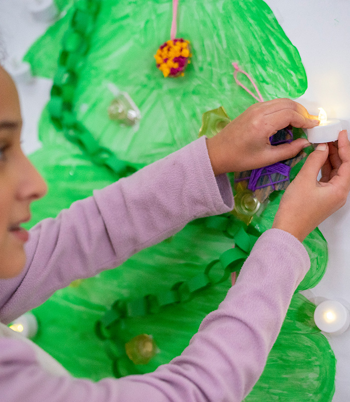 Ein Kind dekoriert einen gemalten Weihnachtsbaum. © Mauro Bedoni / Save the Children Ein Kind dekoriert einen gemalten Weihnachtsbaum.