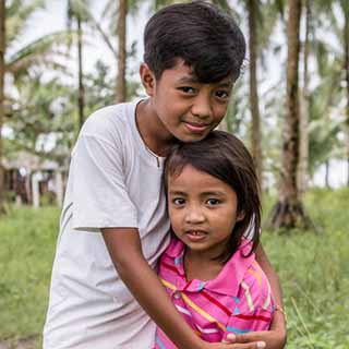 Gerald, 12 Jahr alt, umarmt seine sechsjährige Schwester Xyril vor ihrem Haus auf den Philippinen.