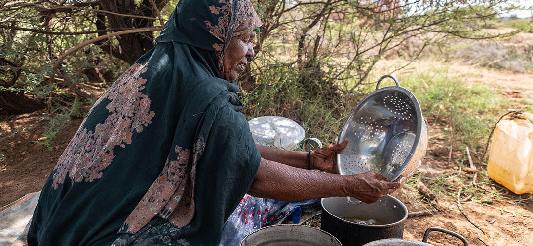 Auch Ayaan machte sich große Sorgen um ihr Enkelkind. © Mustafa Saeed / Save the Children Eine Frau sitzt auf dem Boden und spült Geschirr.