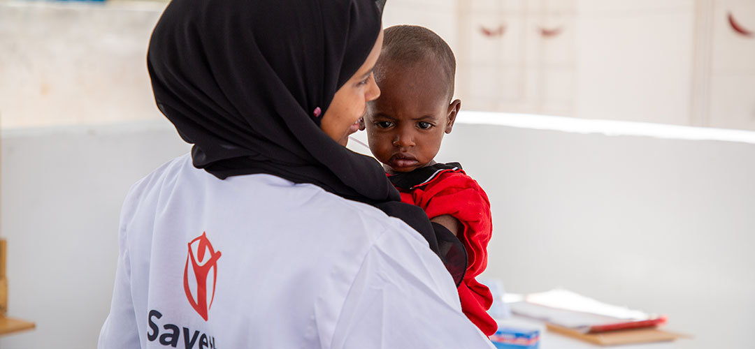 Abdi im Gesundheitszentrum von Save the Children © Mustafa Saeed / Save the Children Ein kleiner Junge auf dem Arm einer Gesundheitshelferin von Save the Children.