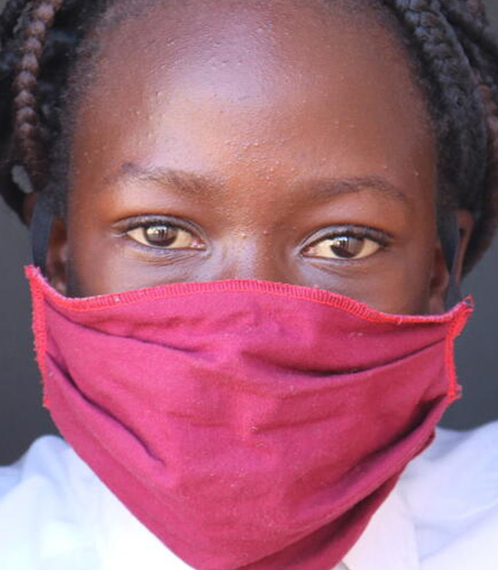 Ein Mädchen trägt eine Maske, um sich vor dem Coronavirus zu schützen, die sie von Save the Children erhalten hat.