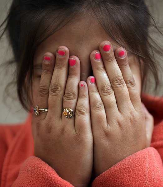 Ein Mädchen verdeckt ihr Gesicht mit den Händen. © Chris de Bode / Save the Children