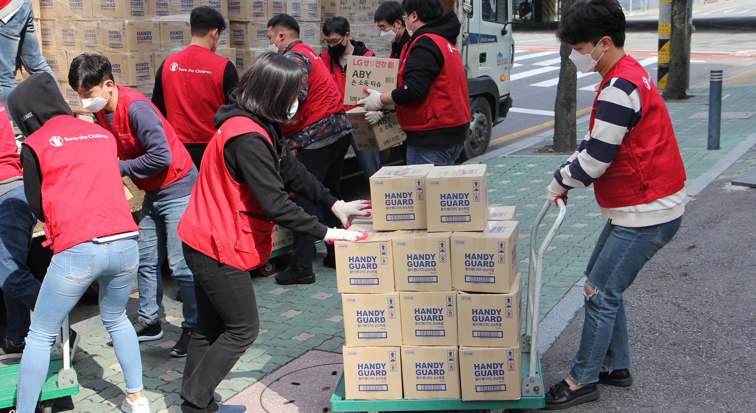 Mitarbeiterinnen und Mitarbeiter von Save the Children Südkorea verpacken Schutzausrüstung wie Gesichtsmasken und Hand-Desinfektionsmittel für den Einsatz gegen Corona. © Save the Children