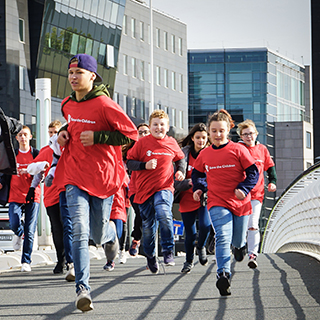 Kinder mit Save the Children T-shirts rennen, während sie an einem Projekt von Save the Children zu Gesundheit und Ernährung teilnehmen